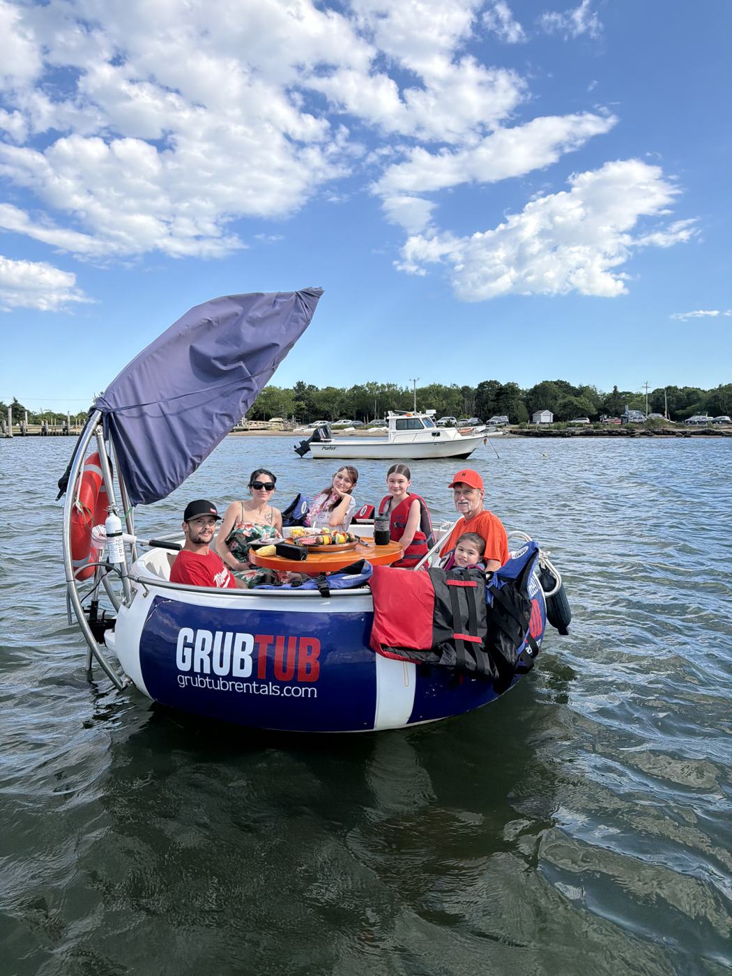 A family waving from a GrubTub on a sunny day