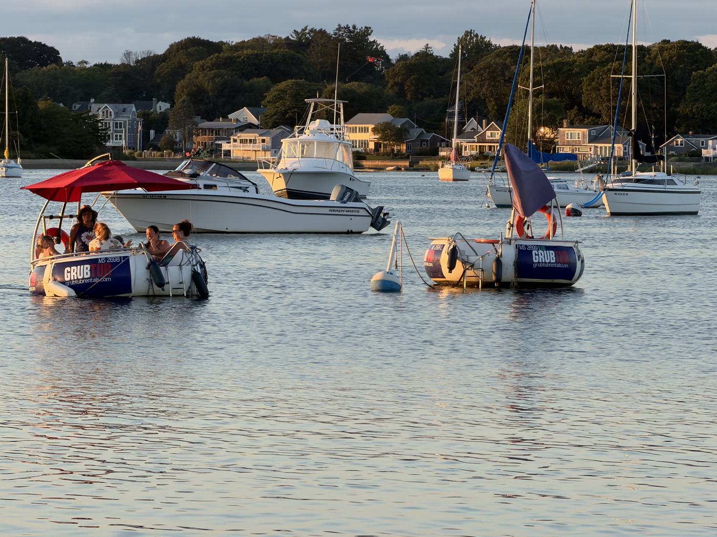 A GrubTub cruising among moored boats in Padanaram Harbor